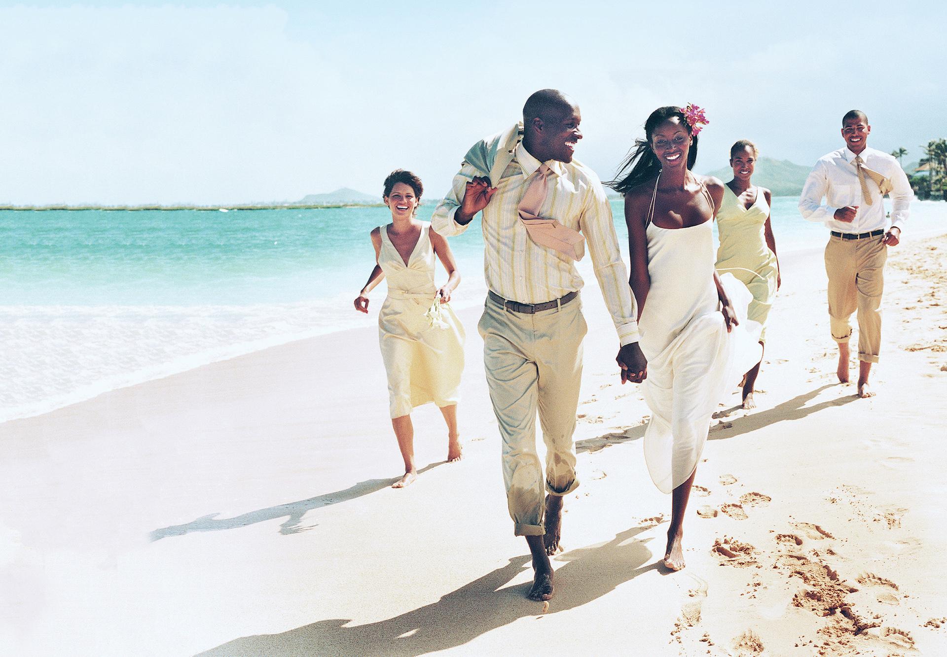 Destination wedding party running along the beach