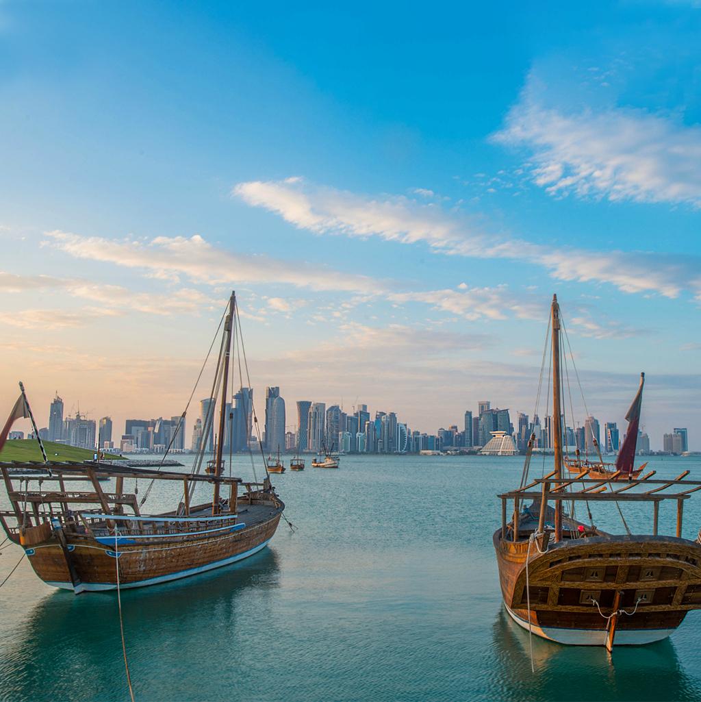 local boats in the waters of Qatar with the skyline in the distance
