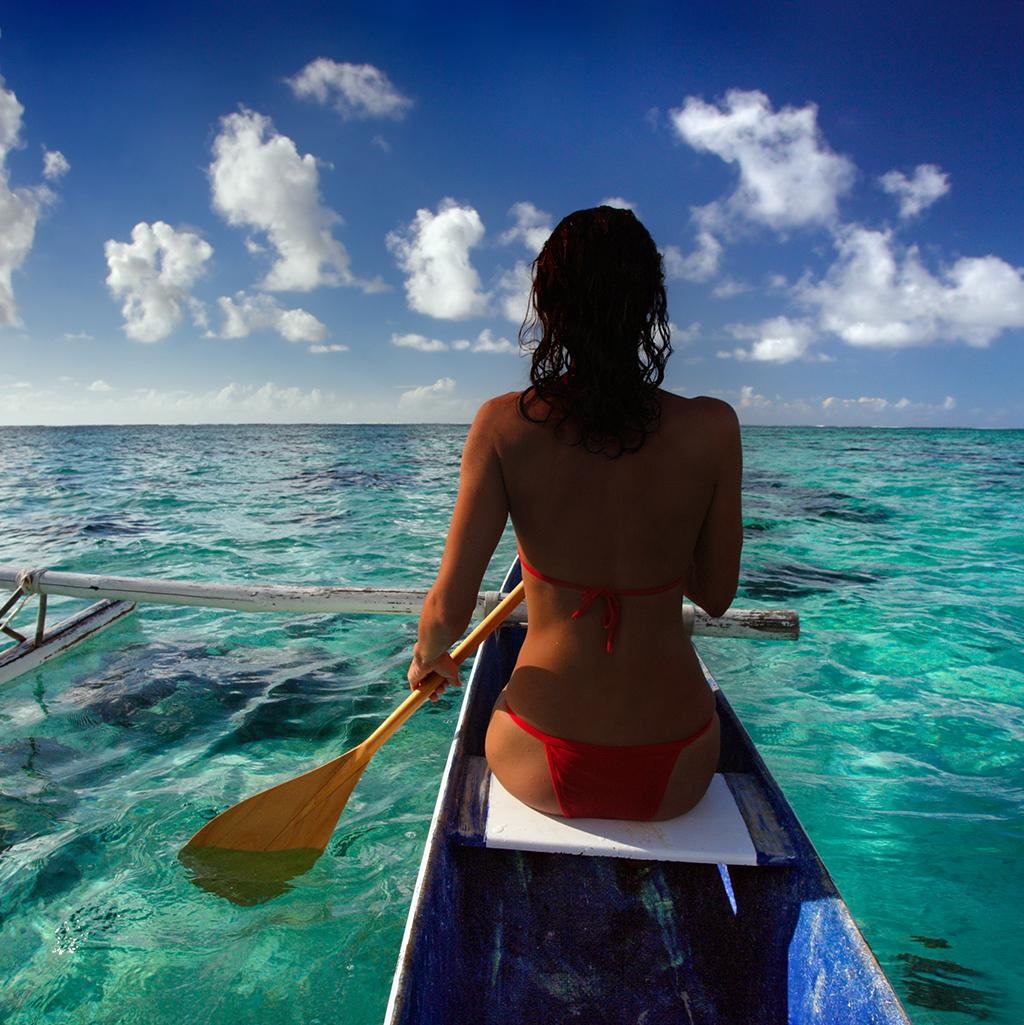 Woman paddling a traditional canoe in Moorea